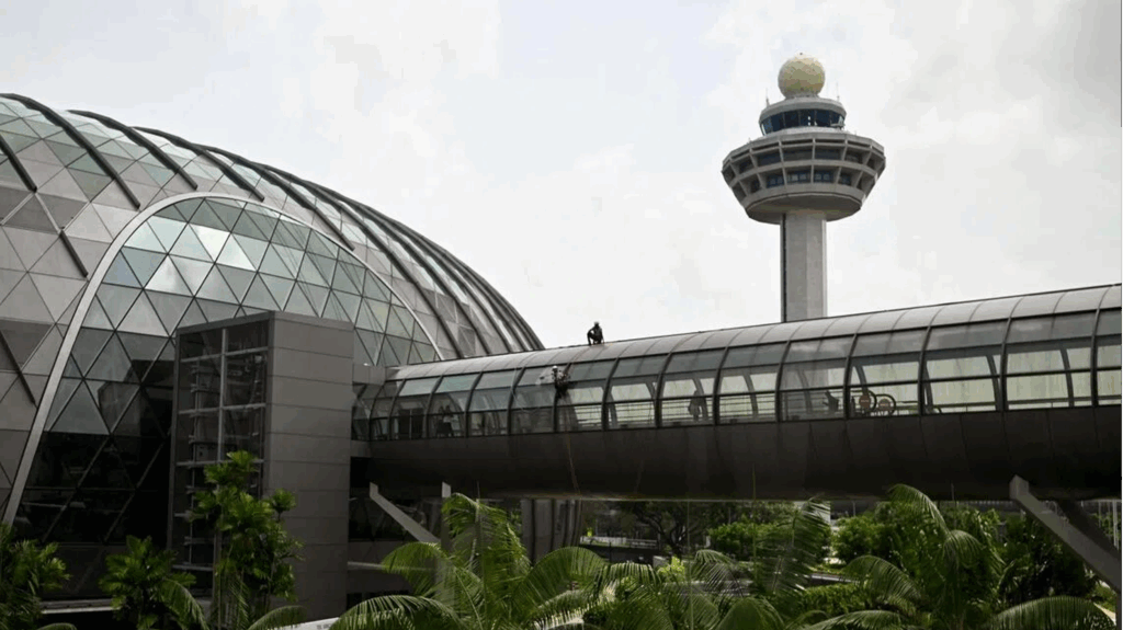 Modern airport terminal with futuristic glass architecture and an observation tower in the background.